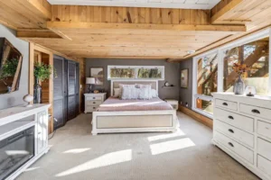 Bedroom with large bed, wood ceilings, and windows
